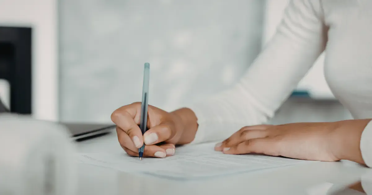 person with pen on hand signing a document