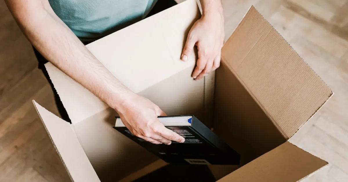 A young adult packing a box with books