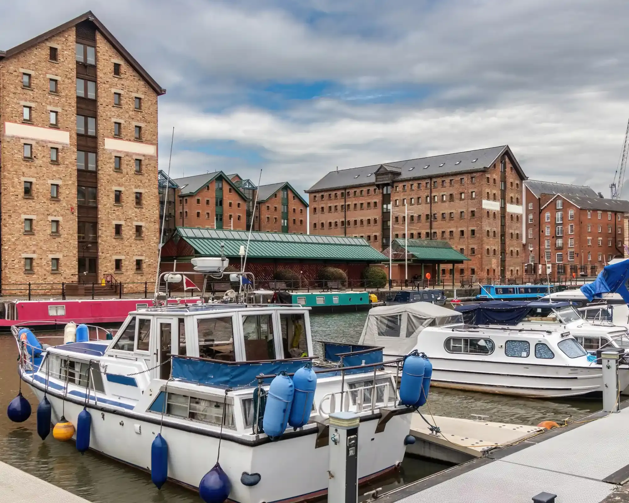 Victorian brick warehouses converted to apartments at Gloucester Docks, with narrowboats and cruisers moored in the basin.