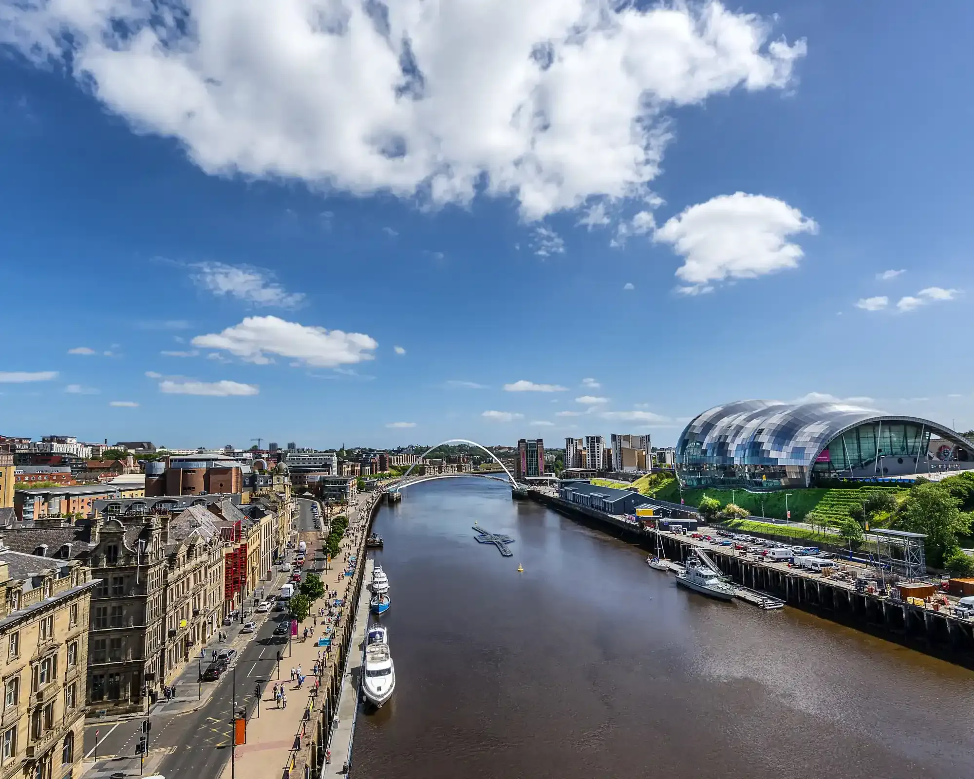 Aerial view of Newcastle Quayside along the River Tyne, featuring the Gateshead Millennium Bridge and the Sage Gateshead