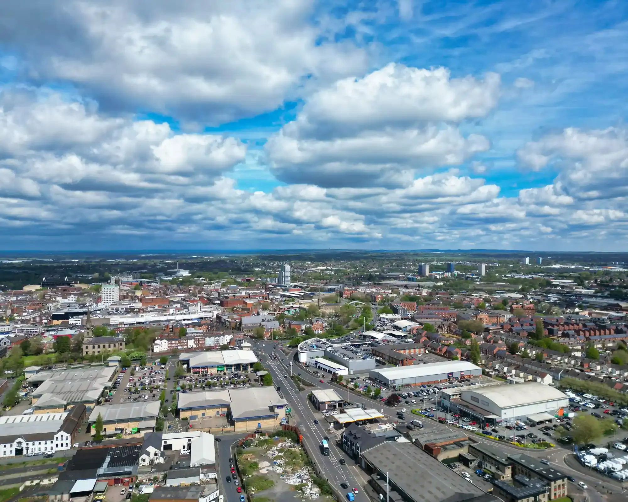 Aerial view of Wolverhampton city centre under a cloudy sky, with retail parks and red-brick terraces in the foreground.