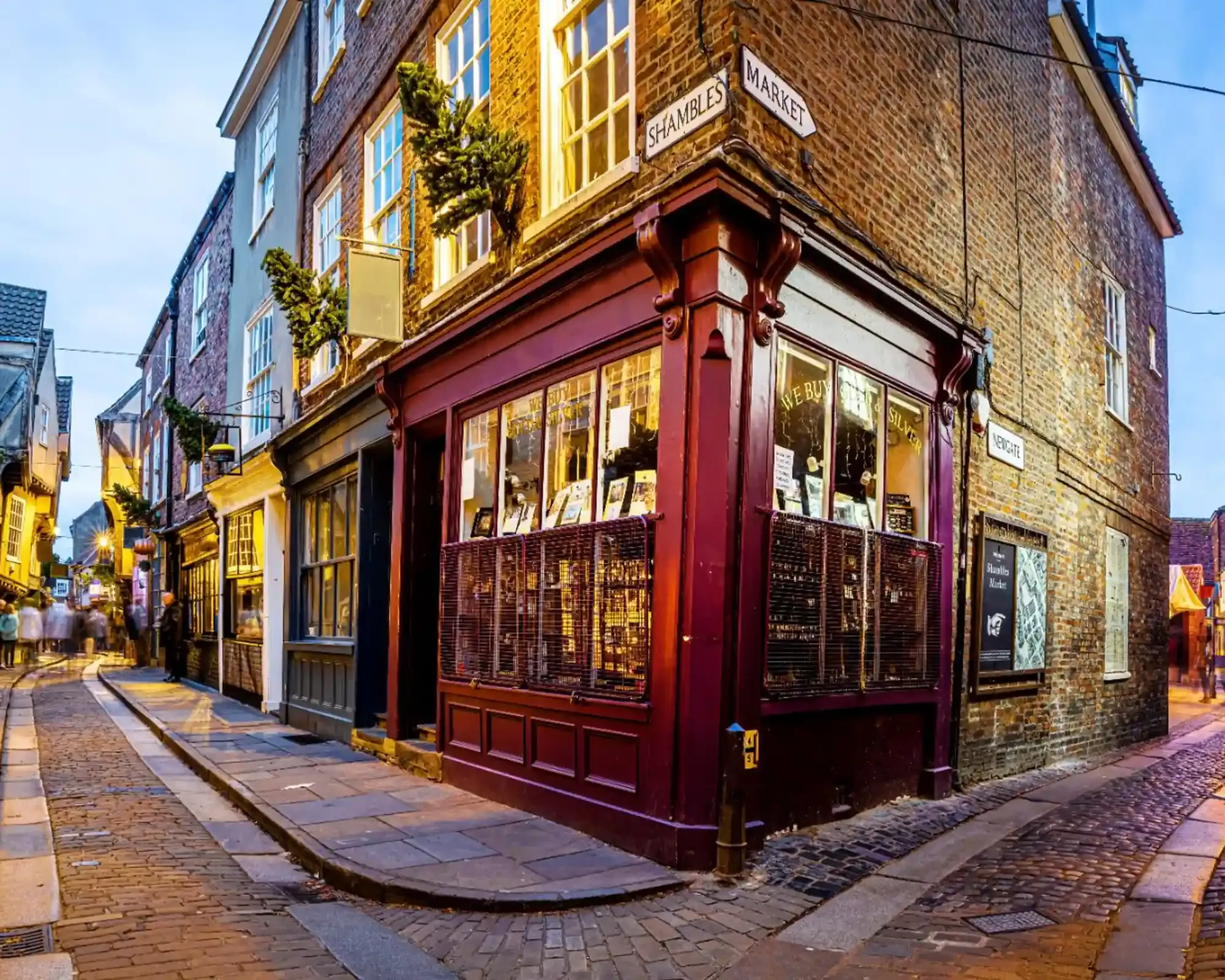 The Shambles in York at dusk, with cobbled streets, timber-framed buildings and the corner of Shambles Market and Newgate.