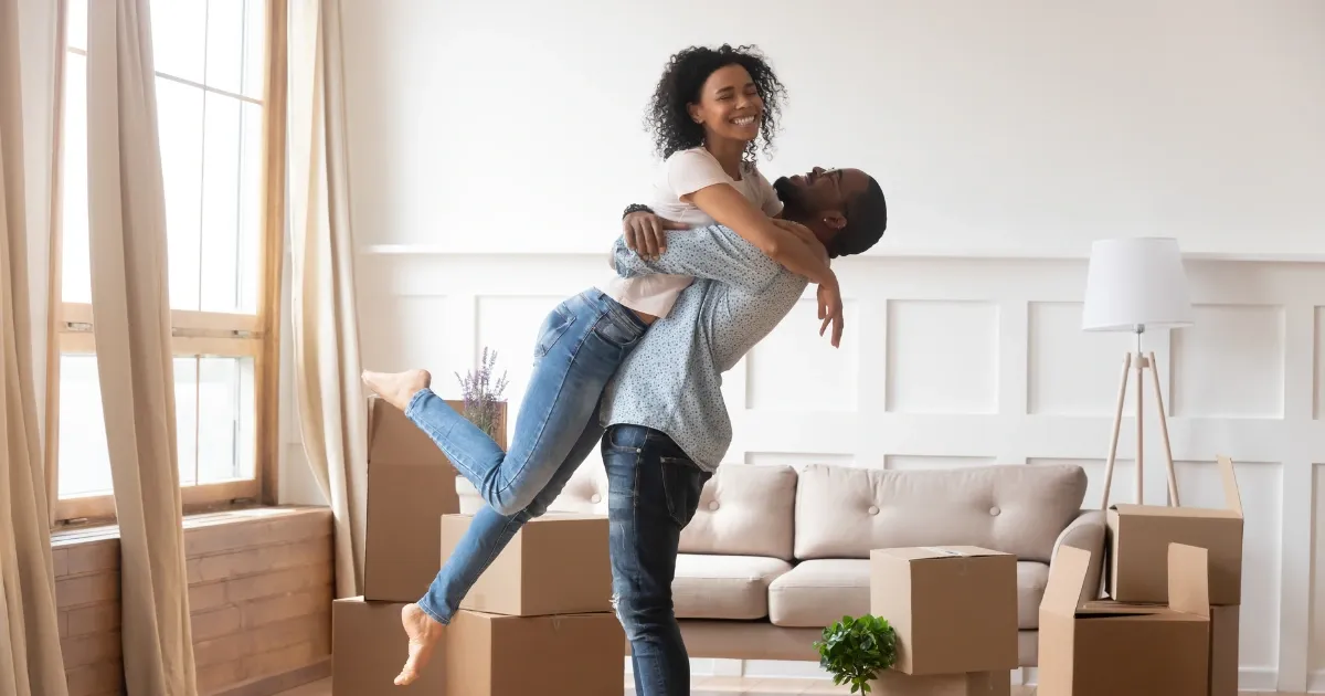 A couple celebrating in a sitting room with boxes around them.