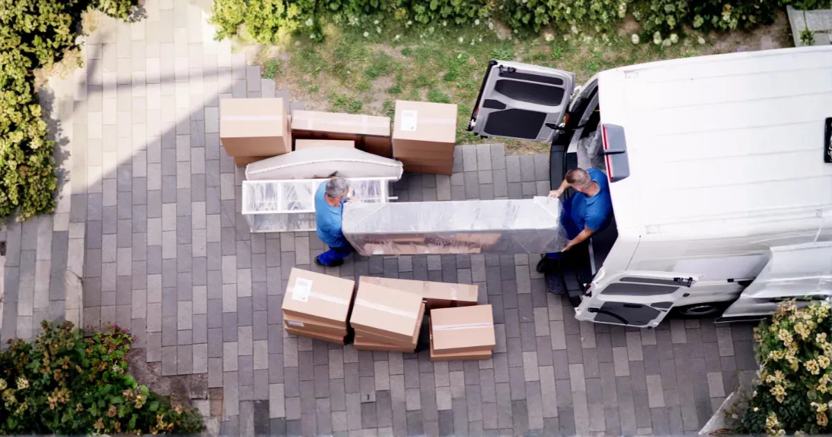 Two men loading boxes into a removal van.