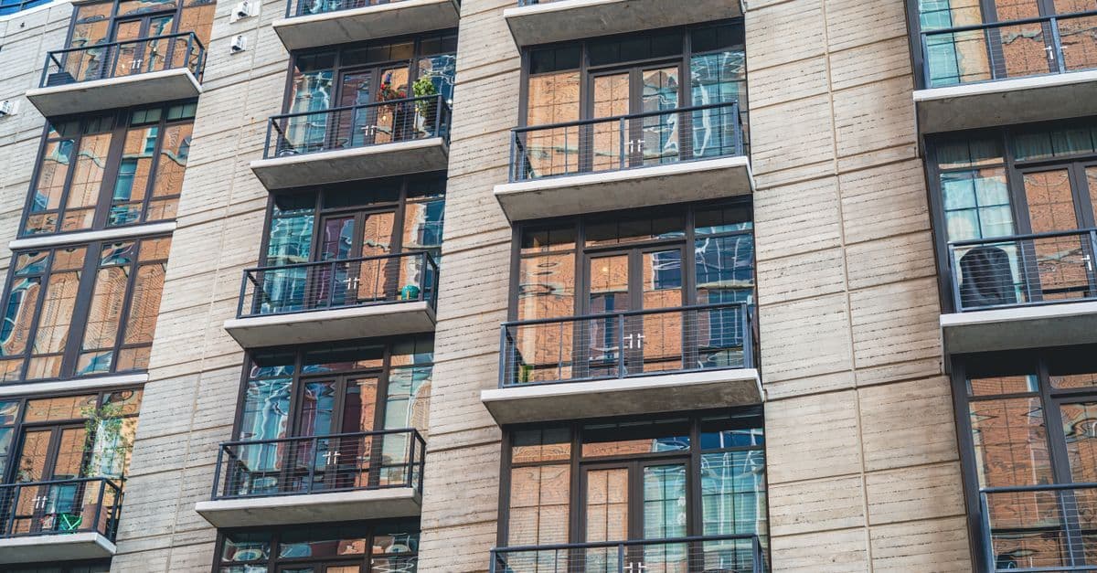 Contemporary apartment building exterior with concrete facade and glass balconies.