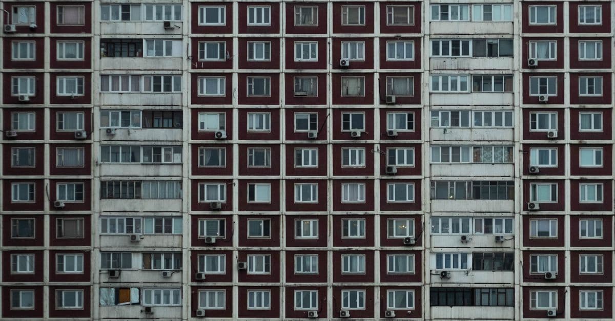 Symmetrical view of an urban apartment block with uniform windows and balconies.