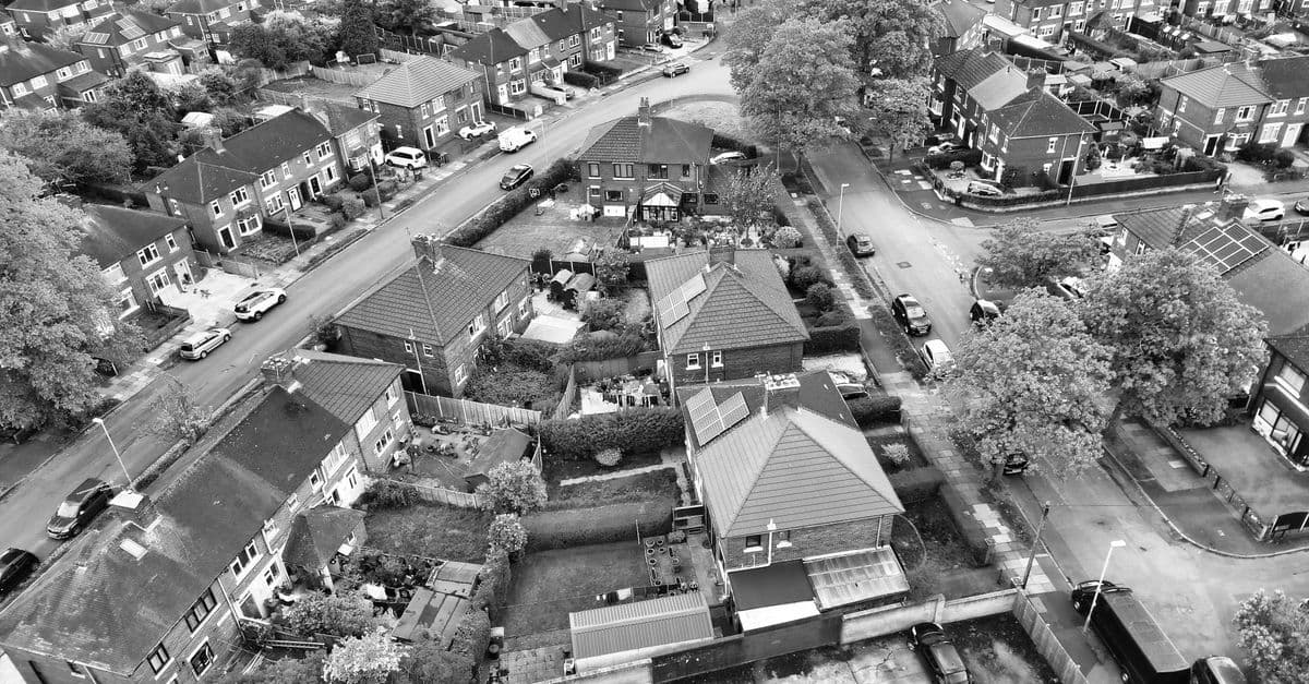 Aerial view of a suburban neighborhood in black and white, showcasing residential houses and streets.