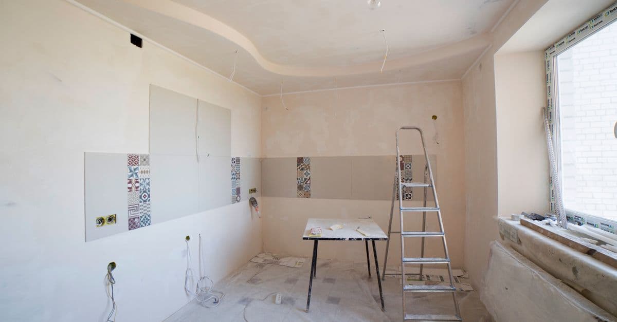 Spacious kitchen under renovation with ladder and tools, showcasing a fresh new design.