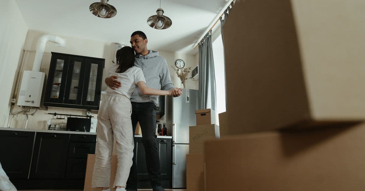 Happy couple dancing together in their new home filled with moving boxes, celebrating new beginnings.