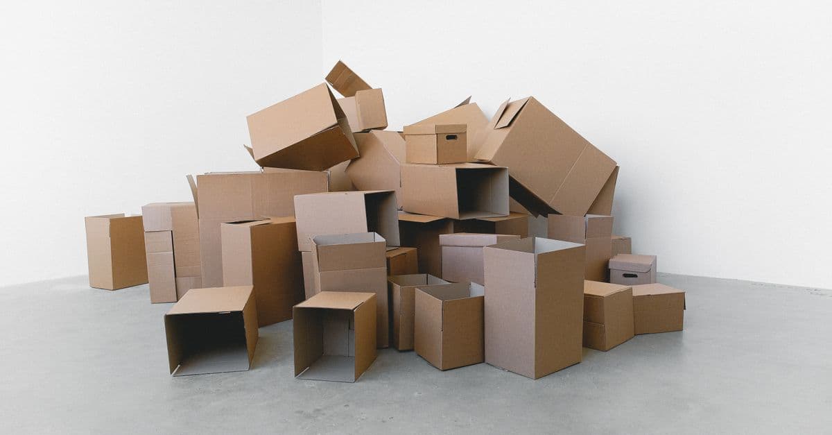 Pile of cardboard containers prepared for relocation on floor at home in daylight on white background