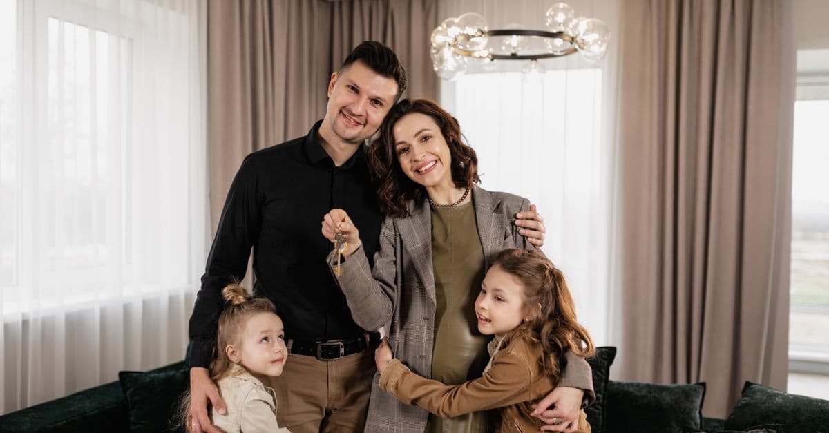 A joyful family holding keys, celebrating their new home indoors.