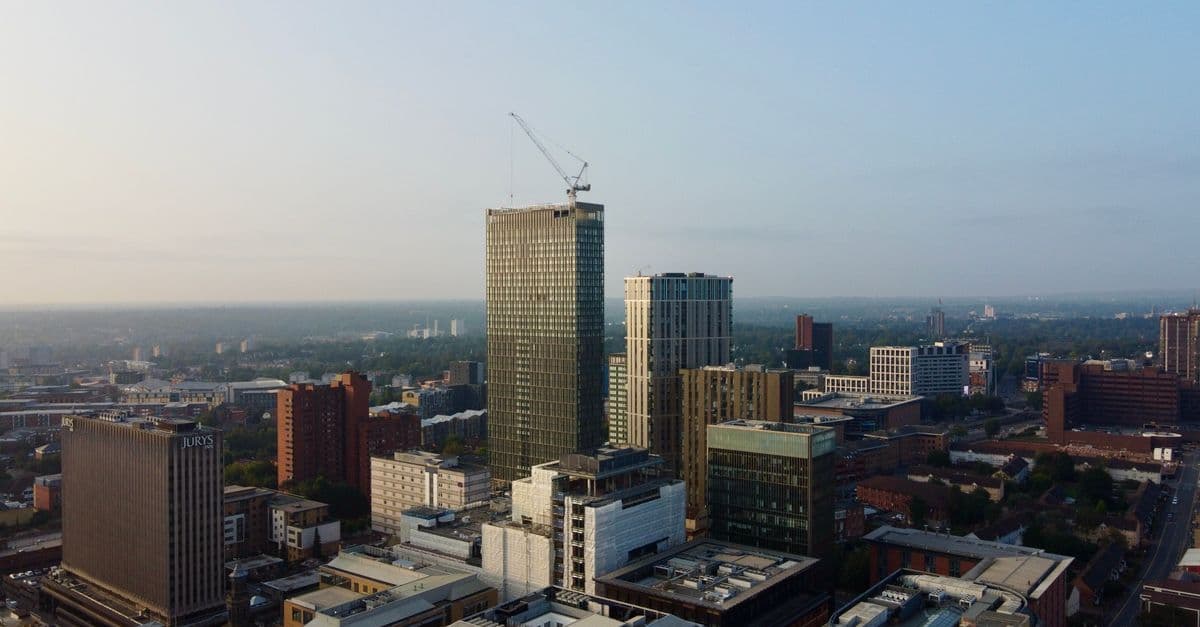 Aerial view of Birmingham’s skyline showcasing tall buildings and vast cityscape under a clear sky.