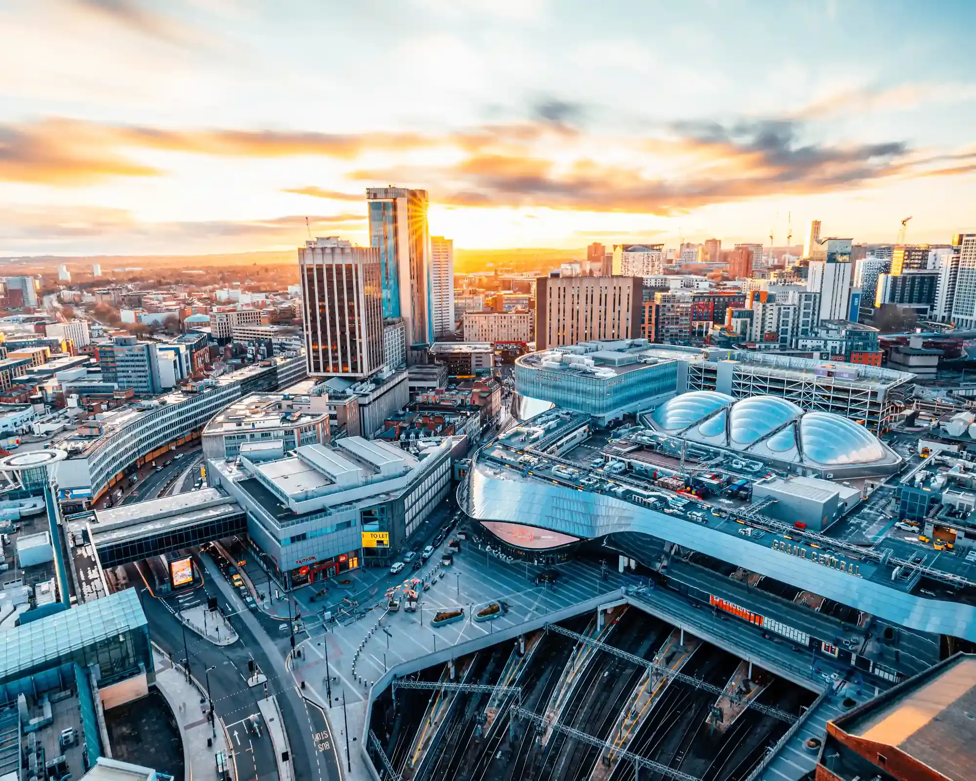 Aerial view of Birmingham city centre at sunset, with Grand Central and New Street station in the foreground.