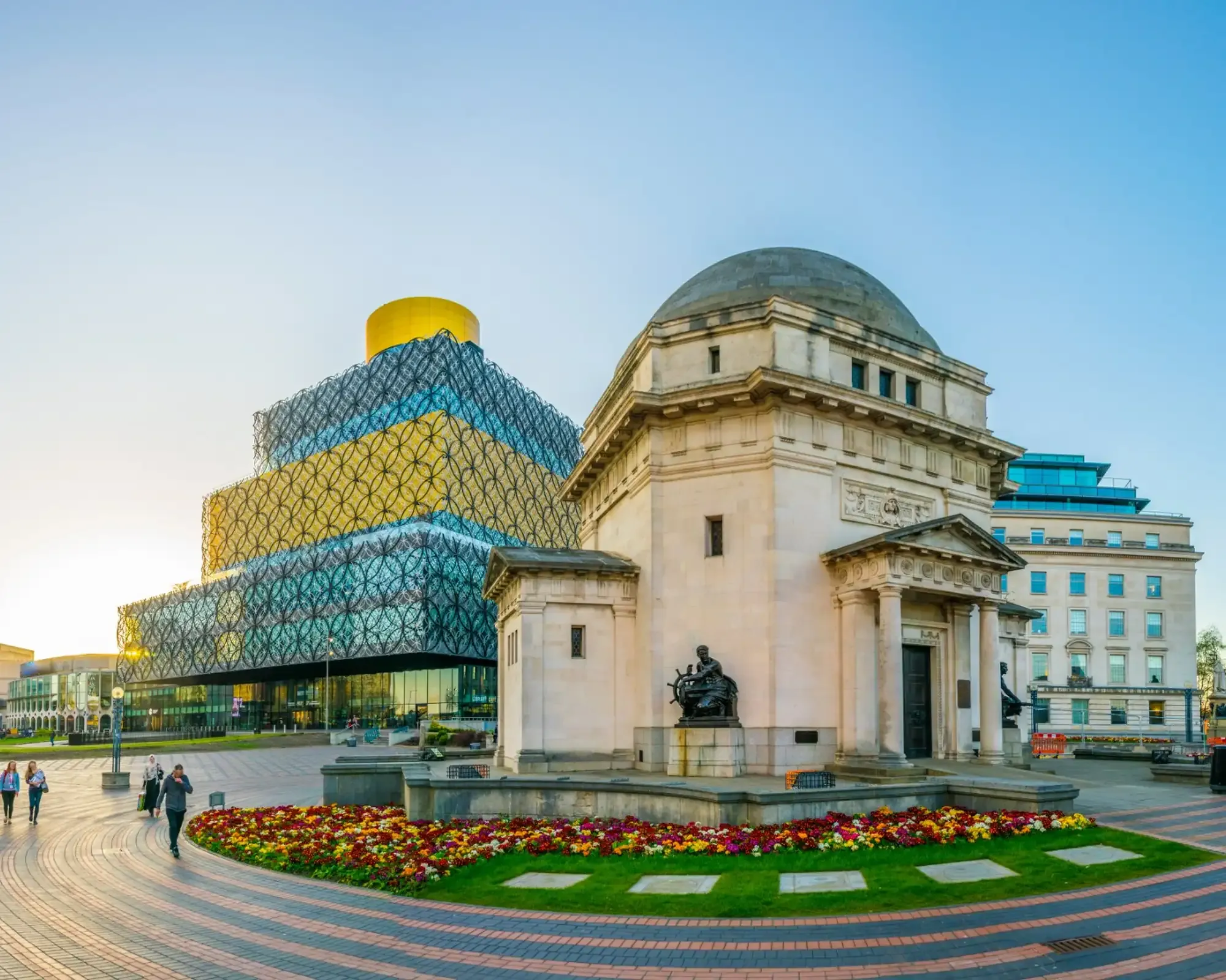 The Library of Birmingham and the Hall of Memory in Centenary Square, with colourful flower beds in the foreground.