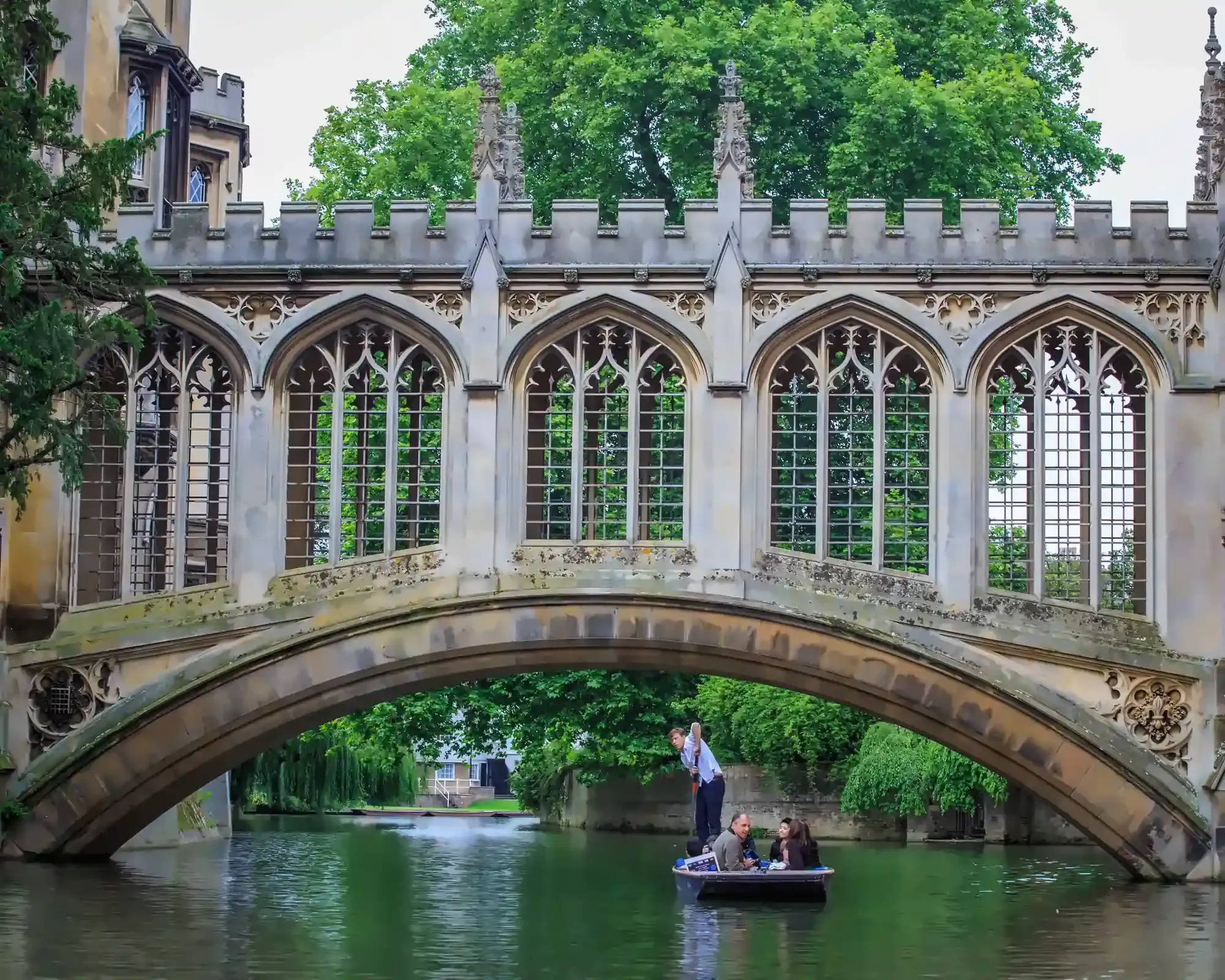 The Bridge of Sighs at St John's College, Cambridge, with a punt carrying passengers beneath its stone arch on the River Cam.