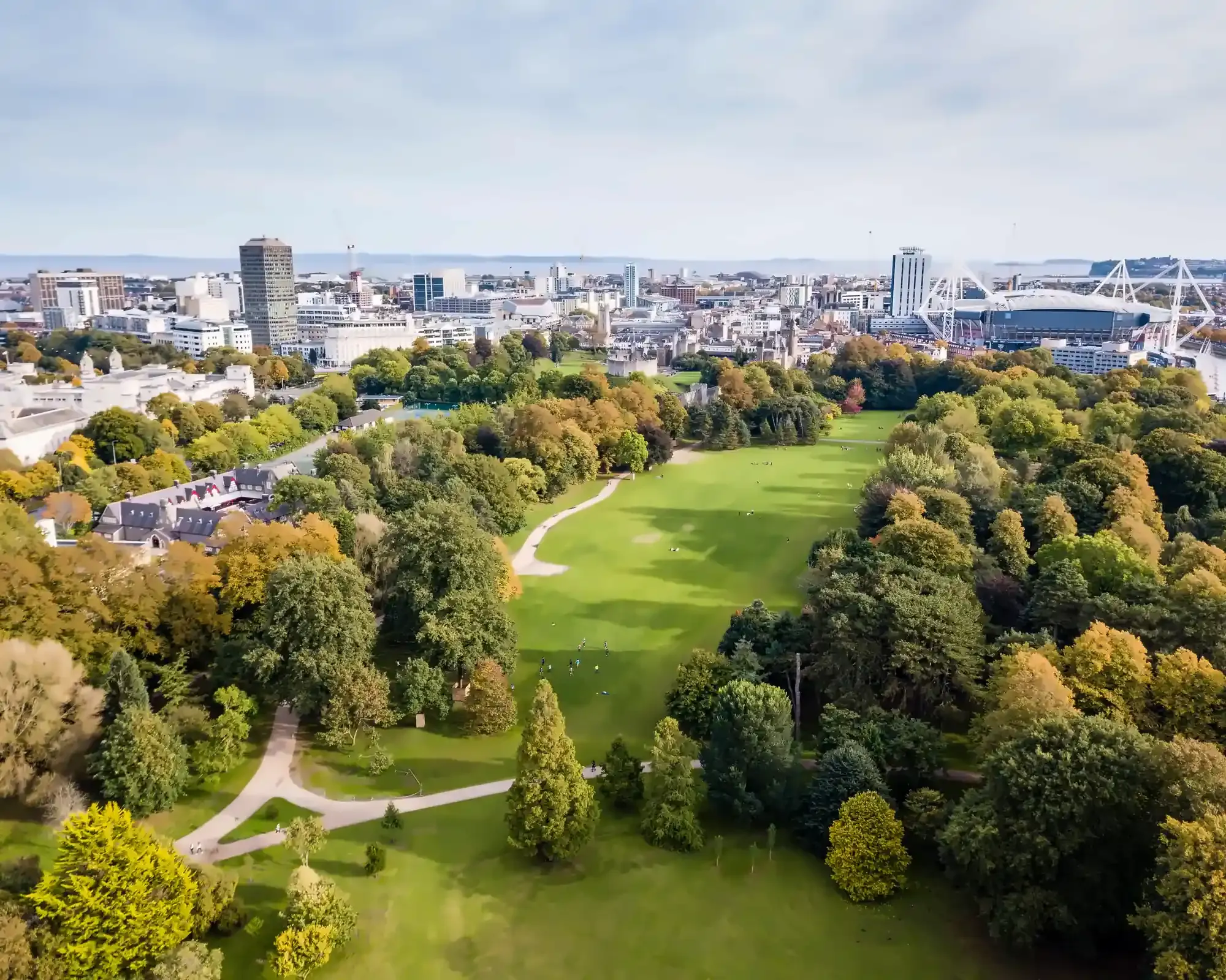 Aerial view of Bute Park in Cardiff in autumn, with the city centre, Cardiff Castle and the Principality Stadium beyond the trees.