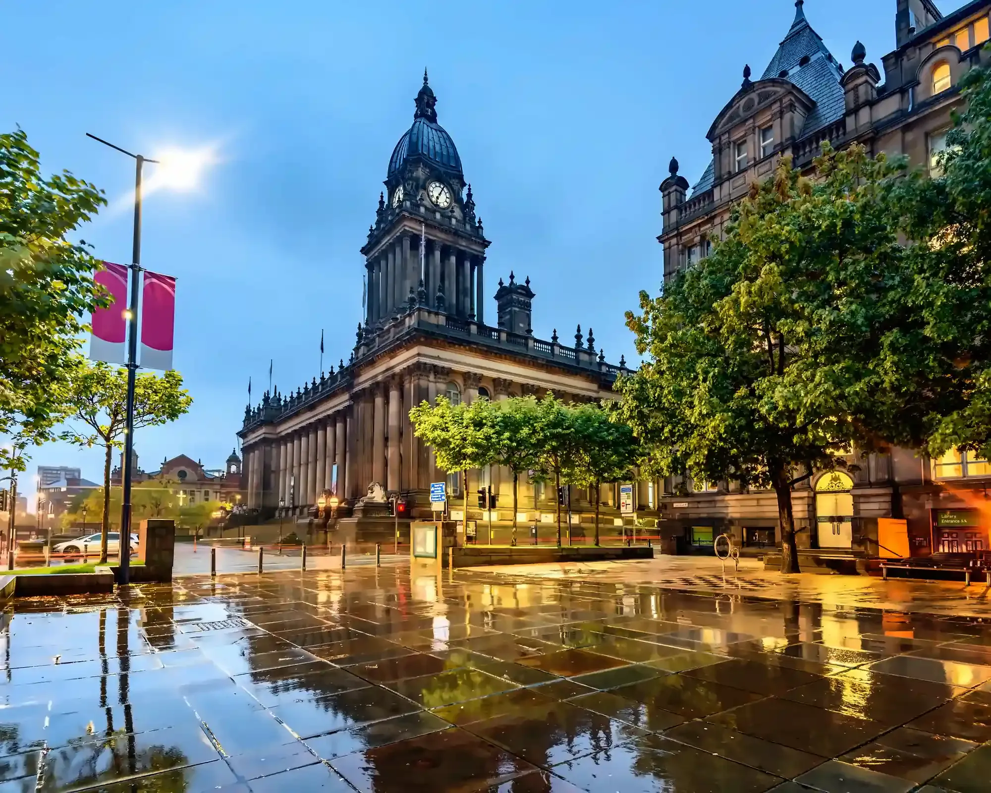 Leeds Town Hall and its clock tower at dusk after rain, with streetlights reflecting on the wet paving.
