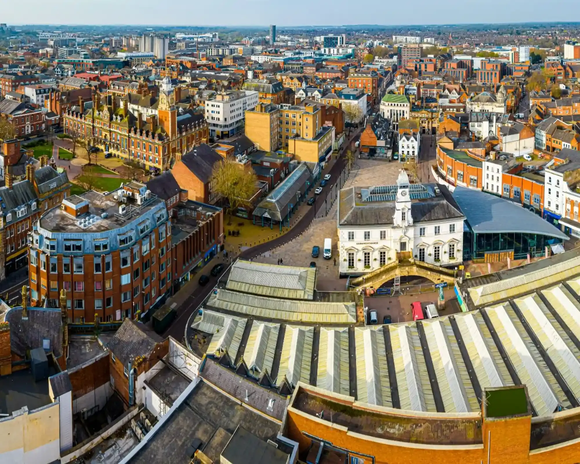 Aerial view of Leicester city centre, with the Corn Exchange and Market Place in the foreground and the Town Hall and red-brick streets beyond.