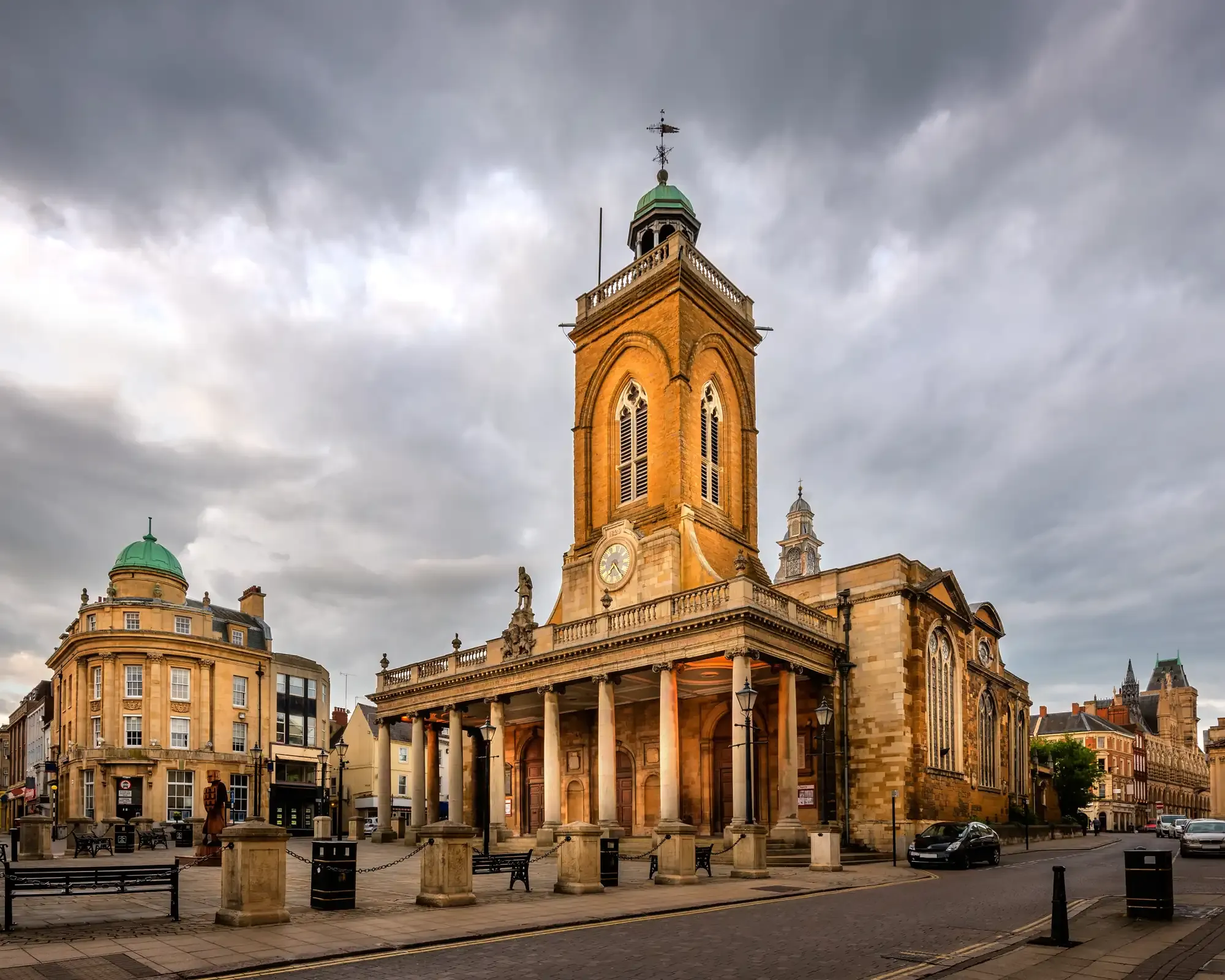 All Saints’ Church in Northampton town centre, with its columned portico and clock tower under a stormy sky.