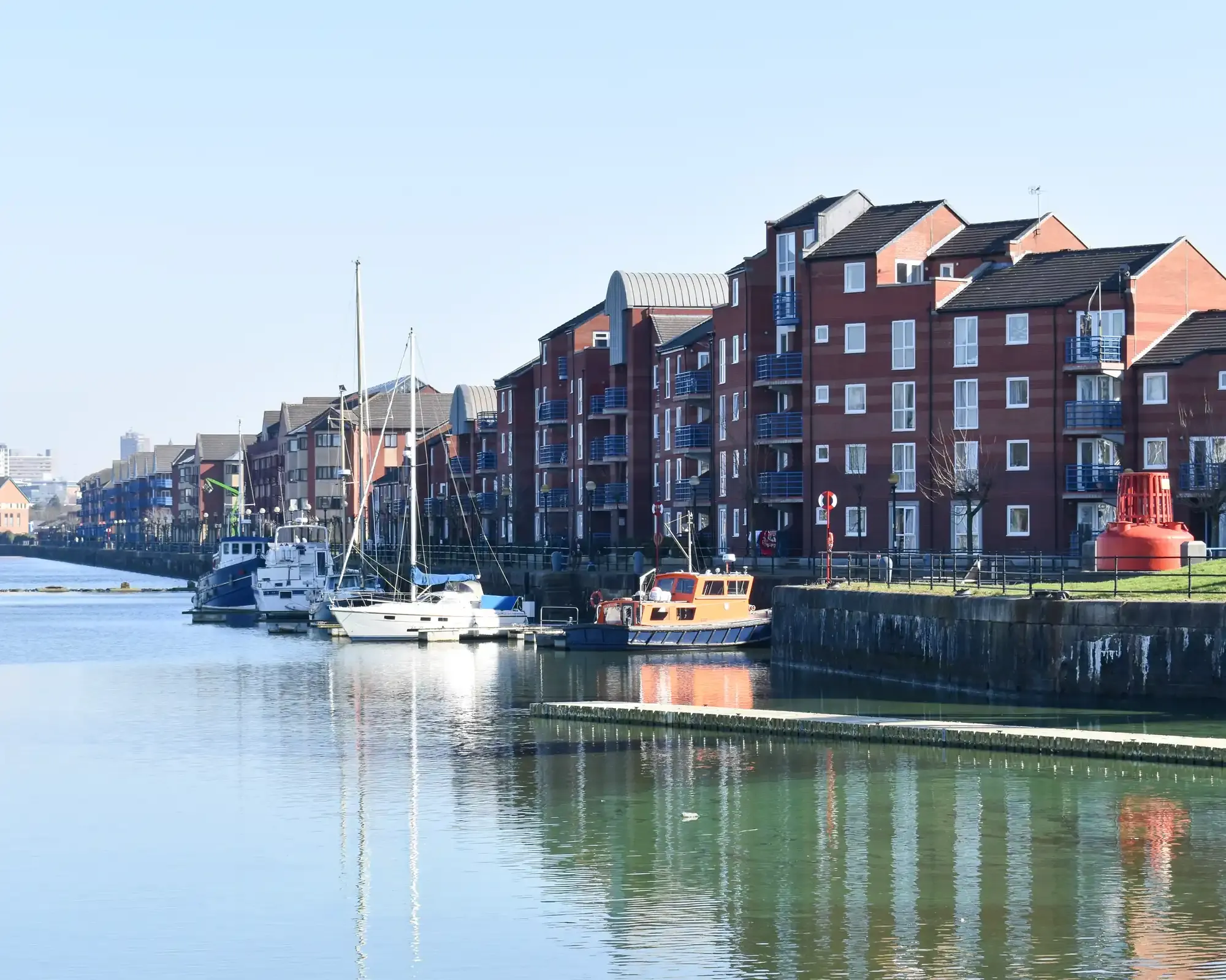 Boats moored in front of red-brick waterside apartments at Preston Marina on Preston Docks.