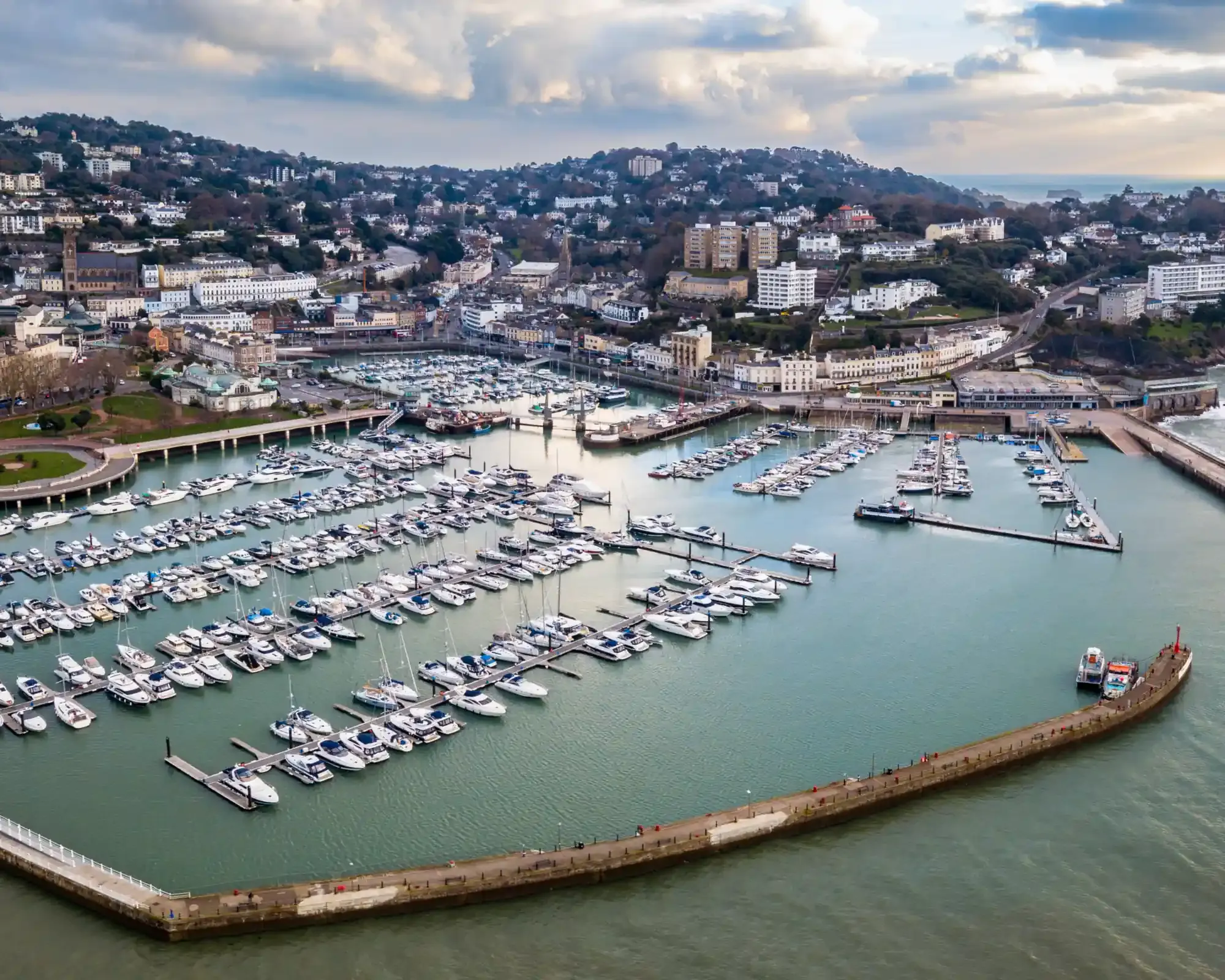 Aerial view of Torquay harbour and marina, with the town rising on the hills behind. The crop keeps the whole harbour wall and the seafront.