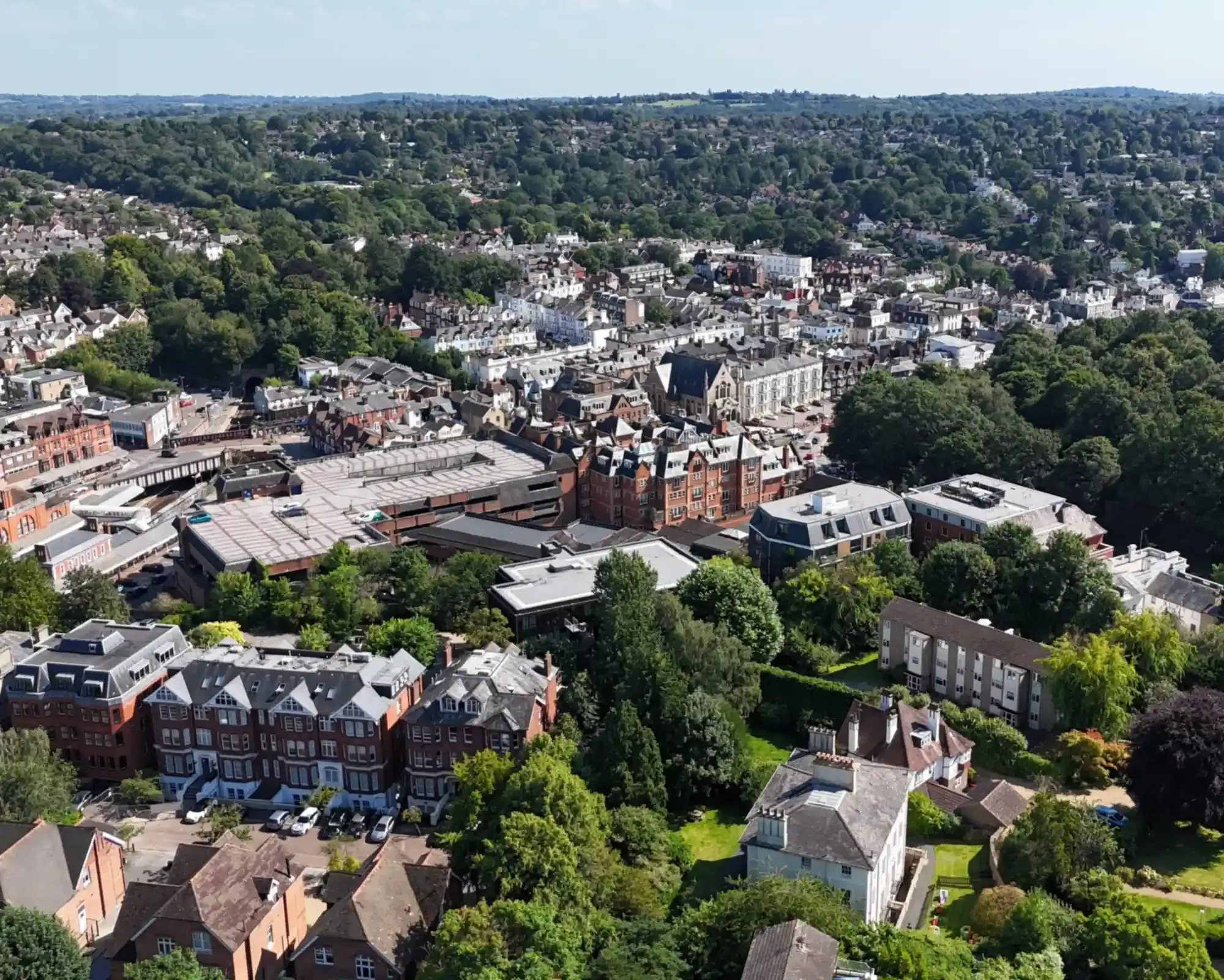 Aerial view of Tunbridge Wells town centre, with Victorian red-brick mansion blocks and wooded hills beyond.